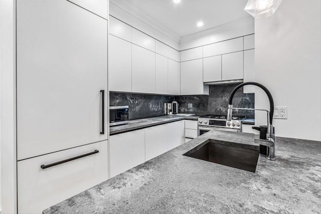 kitchen with ornamental molding, dark stone counters, decorative backsplash, and white cabinets