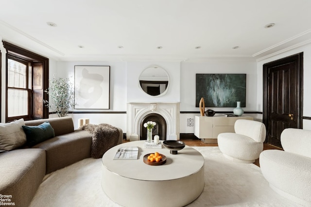 living area featuring recessed lighting, a fireplace with raised hearth, and crown molding