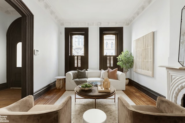 sitting room featuring baseboards, crown molding, and light wood finished floors