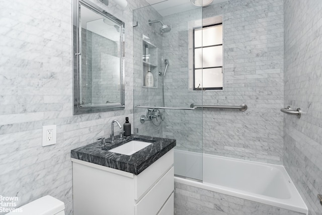 full bathroom featuring tiled shower / bath combo, vanity, tile walls, and toilet