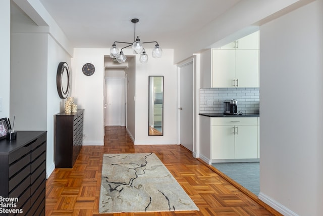 interior space featuring light parquet floors, pendant lighting, white cabinets, and backsplash