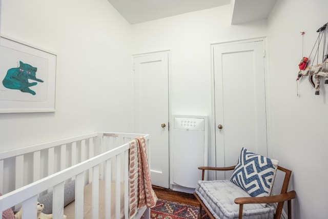 bedroom featuring a crib and dark wood-type flooring