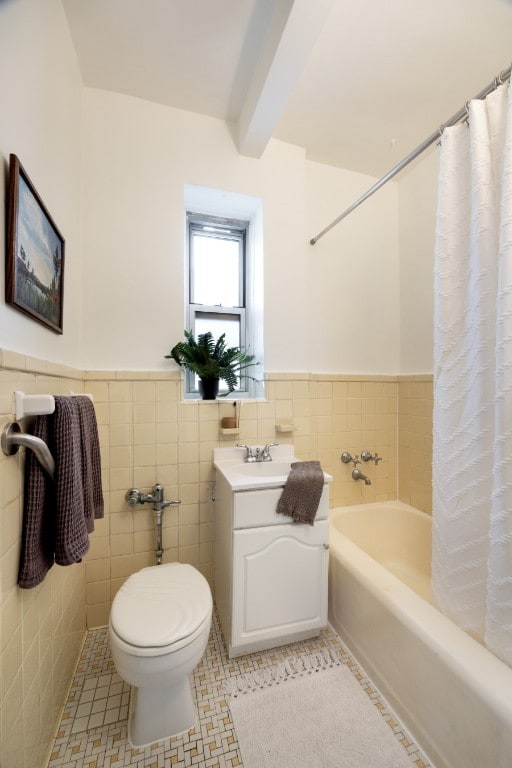 bathroom featuring tile patterned flooring, toilet, tile walls, beamed ceiling, and vanity