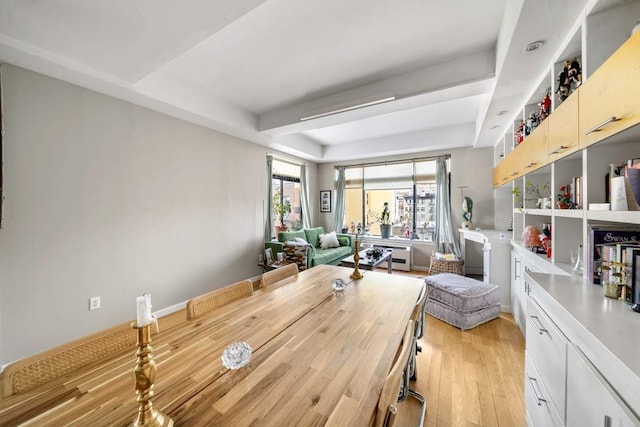 dining area with a tray ceiling and light wood-type flooring