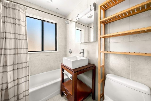 bathroom with visible vents, toilet, vanity, tile walls, and shower / bath combo
