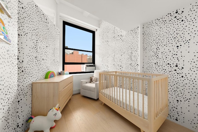 bedroom with a nursery area and light hardwood / wood-style floors