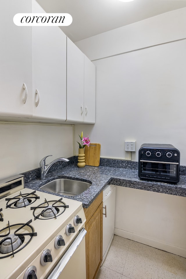 130 8th Ave Unit 7D, New York City, NY 11215 - kitchen with white gas range oven, a sink, dark speckled floor, white cabinets, and dark stone counters