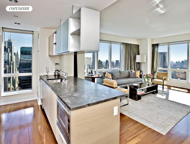 kitchen featuring visible vents, dark wood finished floors, a sink, a view of city, and a wealth of natural light