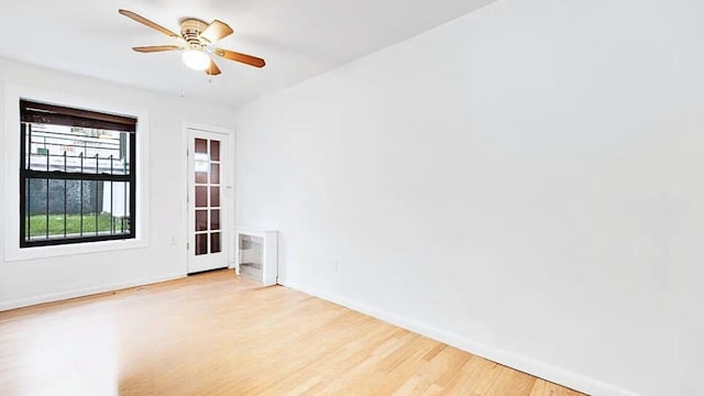 spare room with baseboards, light wood-type flooring, and ceiling fan