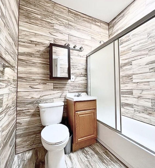 full bathroom with toilet, wood finished floors, vanity, and shower / bath combination with glass door
