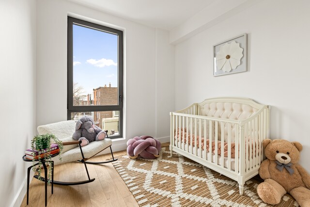450 Grand Ave Unit 4A, New York City, NY 11238 - bedroom featuring multiple windows, wood finished floors, baseboards, and a nursery area