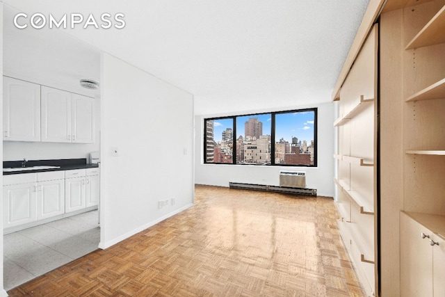 unfurnished living room with a view of city, a sink, visible vents, and baseboards