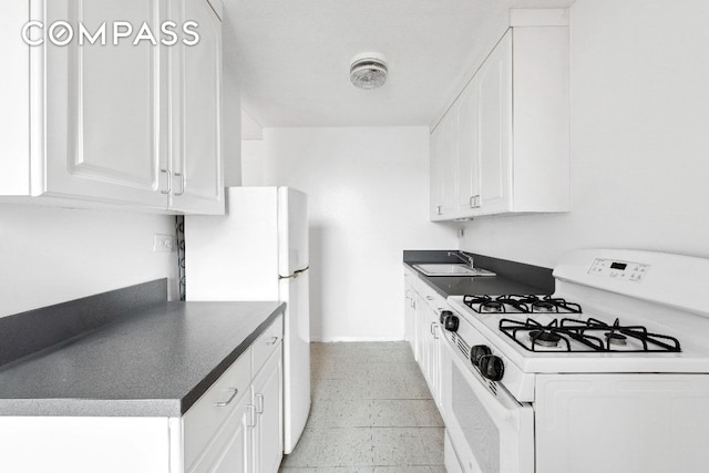 kitchen with white appliances, visible vents, white cabinets, dark countertops, and a sink