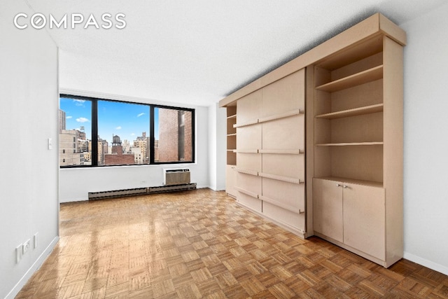 interior space featuring a baseboard heating unit, a view of city, an AC wall unit, and baseboards