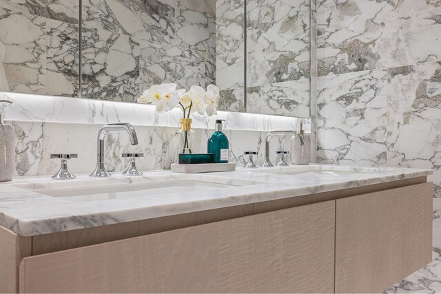 bathroom with double vanity, tile walls, marble finish floor, a garden tub, and a sink