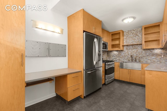 kitchen with appliances with stainless steel finishes, built in desk, sink, and decorative backsplash