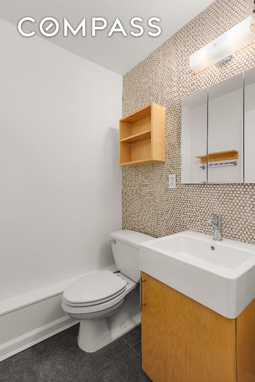 bathroom featuring vanity, toilet, tile patterned flooring, and decorative backsplash