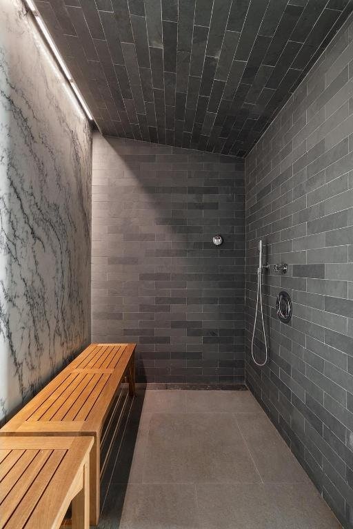 interior space with a shower, tile patterned floors, and tile walls