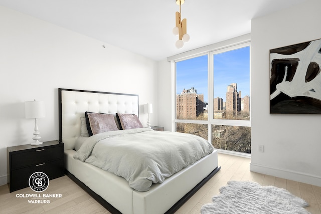 1399 Park Ave Unit 8D, New York City, NY 10029 - bedroom with light wood finished floors, a view of skyline, and baseboards