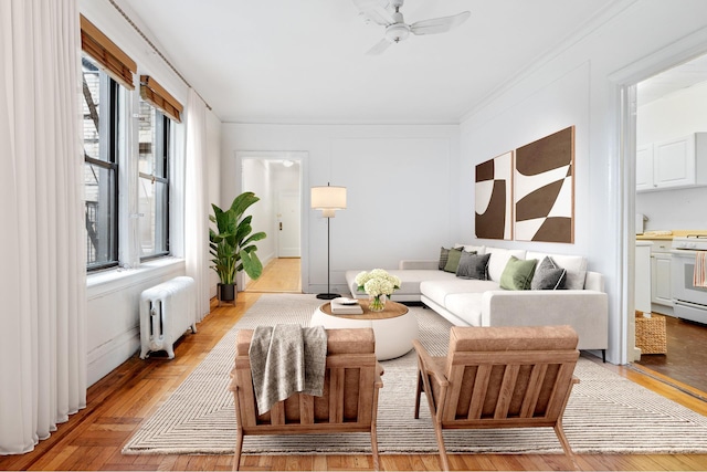 living area featuring ornamental molding, radiator heating unit, and a ceiling fan