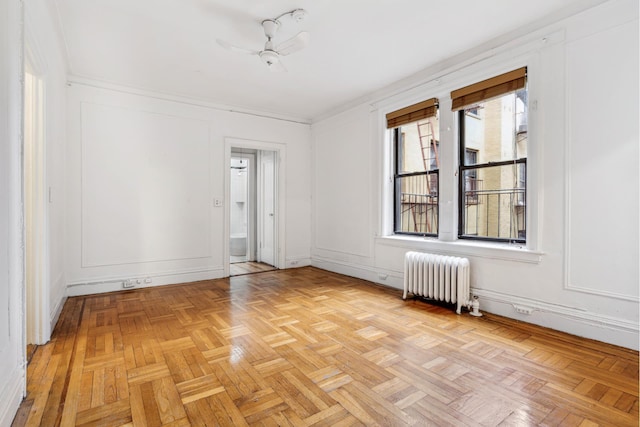 spare room featuring a decorative wall, radiator heating unit, and ceiling fan