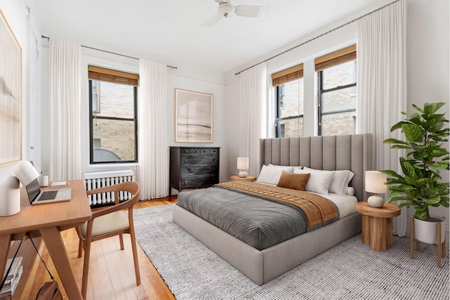 bedroom featuring multiple windows, light wood-type flooring, and radiator