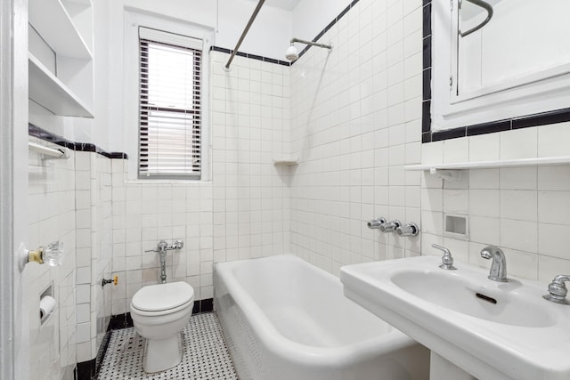 full bathroom featuring tile walls, toilet, washtub / shower combination, and a sink