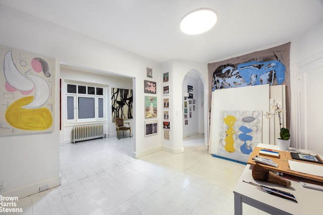 entrance foyer featuring radiator heating unit, arched walkways, and baseboards