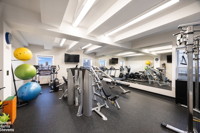 exercise room featuring beamed ceiling and plenty of natural light