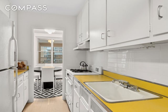 kitchen featuring tasteful backsplash, sink, white cabinets, and white appliances