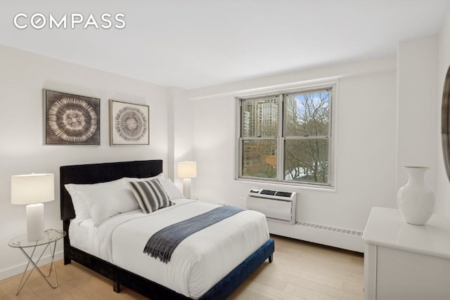 bedroom featuring a wall unit AC and light wood-type flooring