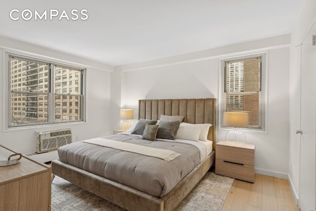 bedroom featuring light hardwood / wood-style floors and a wall unit AC