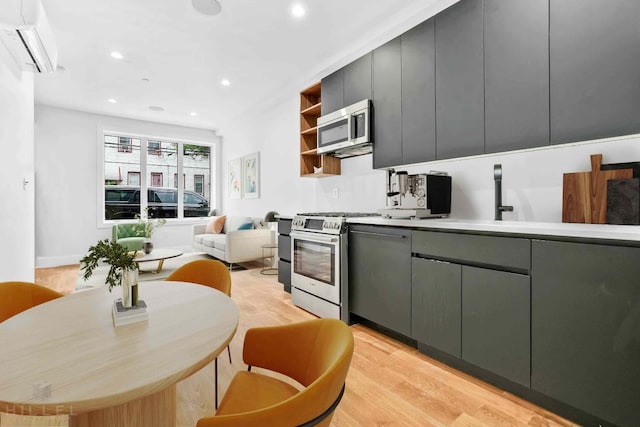 kitchen with a wall unit AC, open shelves, gray cabinets, stainless steel appliances, and light wood-type flooring