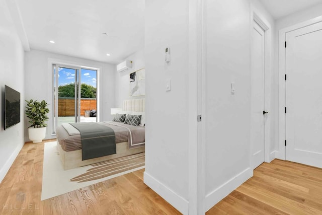 bedroom with baseboards, light wood-style flooring, recessed lighting, an AC wall unit, and access to outside