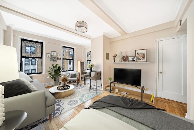 living room featuring a notable chandelier, ornamental molding, baseboards, and hardwood / wood-style floors