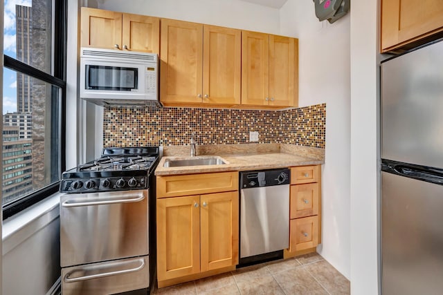 kitchen with a sink, stainless steel appliances, light stone counters, and backsplash