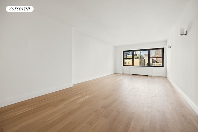 unfurnished room with radiator, visible vents, light wood-style flooring, and baseboards