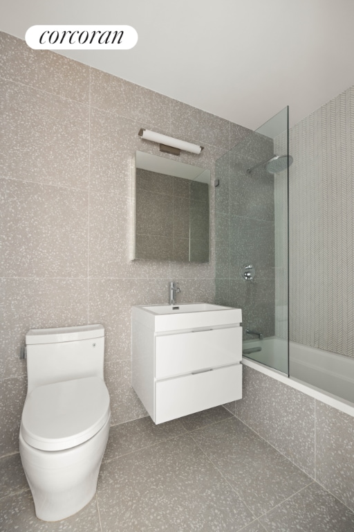 full bathroom with tiled shower / bath combo, vanity, toilet, and tile patterned flooring