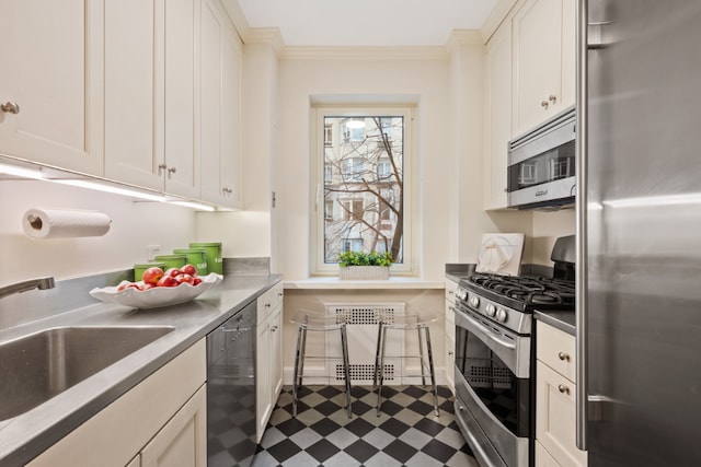 kitchen featuring dark floors, crown molding, appliances with stainless steel finishes, white cabinetry, and a sink