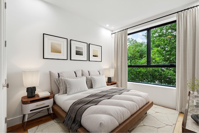 bedroom with recessed lighting, multiple windows, baseboards, and wood finished floors