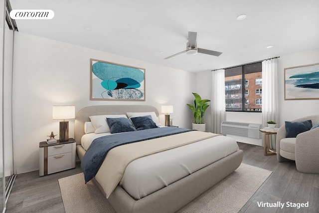 bedroom featuring visible vents, wood finished floors, a ceiling fan, and a wall mounted AC