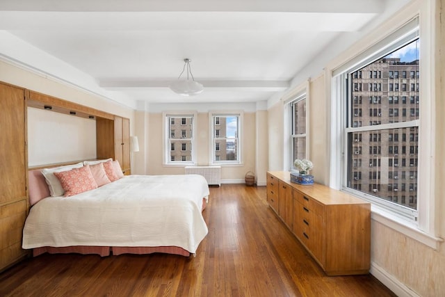 bedroom with beamed ceiling, radiator, and hardwood / wood-style floors