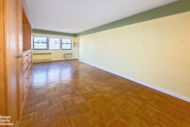 empty room featuring radiator heating unit, a wall mounted AC, and dark parquet floors