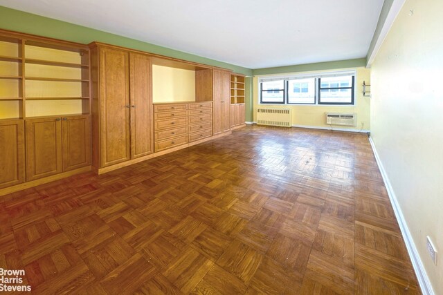 empty room featuring radiator heating unit, baseboards, and an AC wall unit