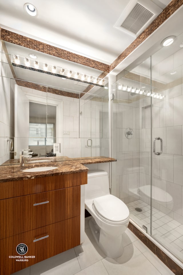 full bathroom featuring toilet, tile patterned flooring, a shower stall, vanity, and tile walls