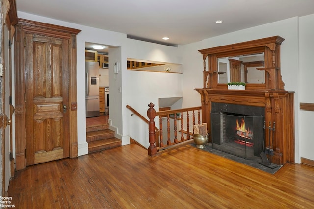 interior space featuring a fireplace with flush hearth, recessed lighting, baseboards, and wood finished floors