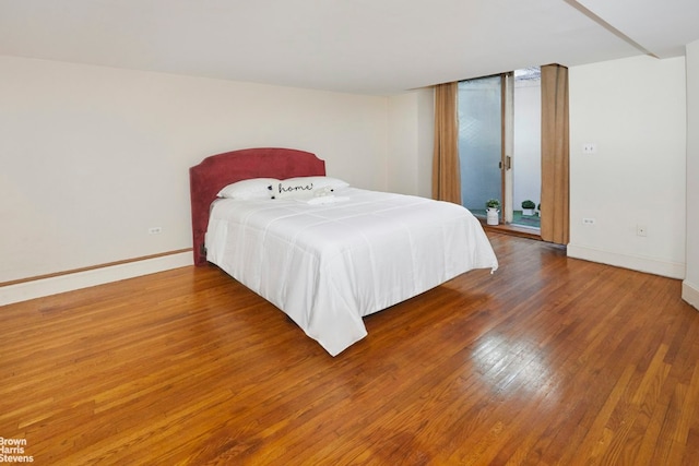 bedroom with access to exterior, baseboards, and dark wood-style flooring