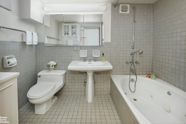 bathroom featuring toilet, visible vents, tile walls, a combined bath / shower with jetted tub, and tile patterned floors