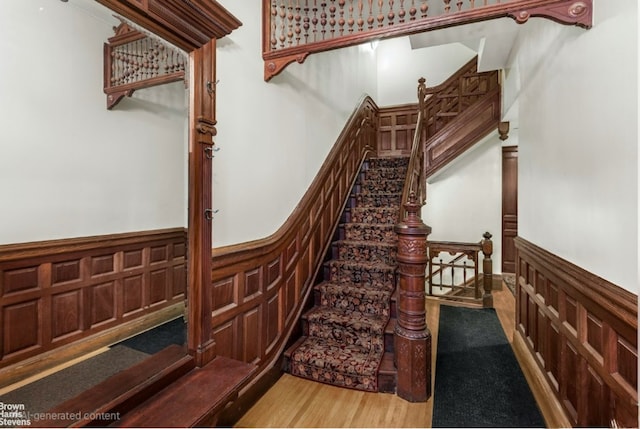 stairs featuring a wainscoted wall and wood finished floors