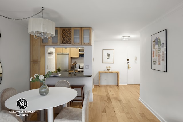 dining area with light wood-style floors, ornamental molding, a chandelier, and baseboards